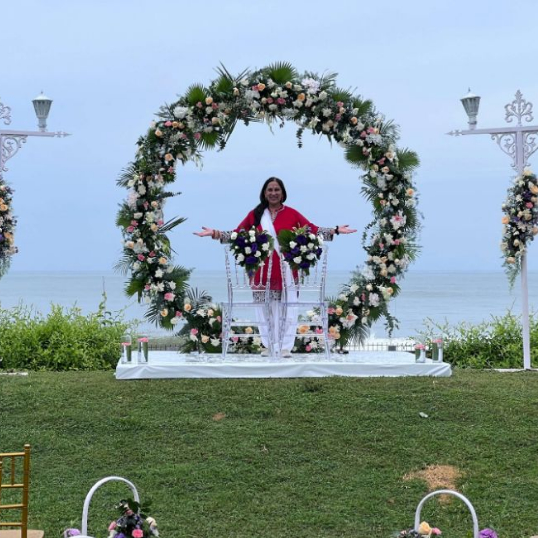 Sonal standing at wedding alter in front of an arch of flowers
