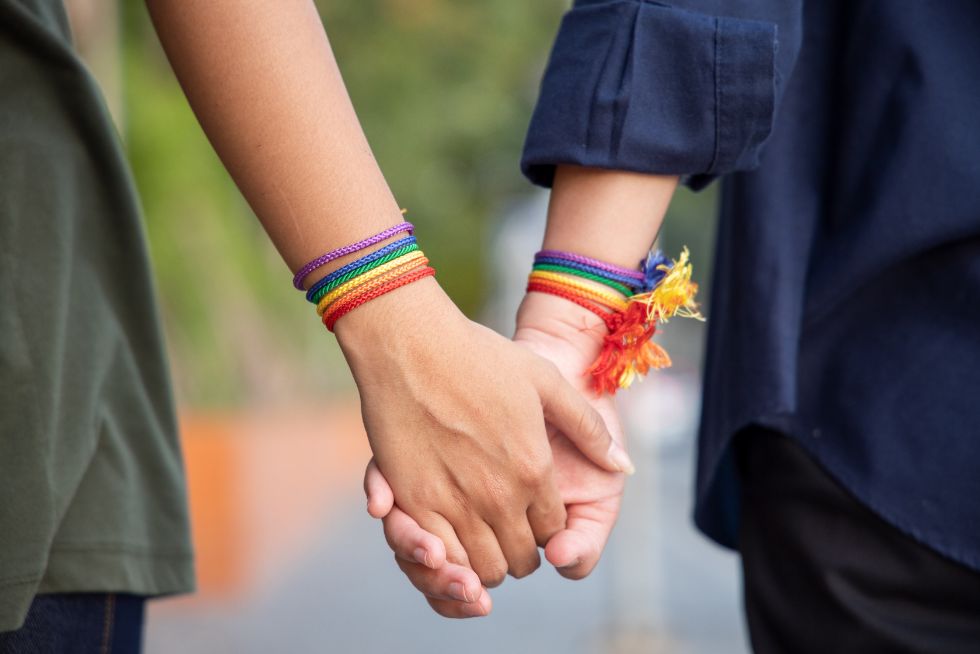 women holding hands with rainbow braclets